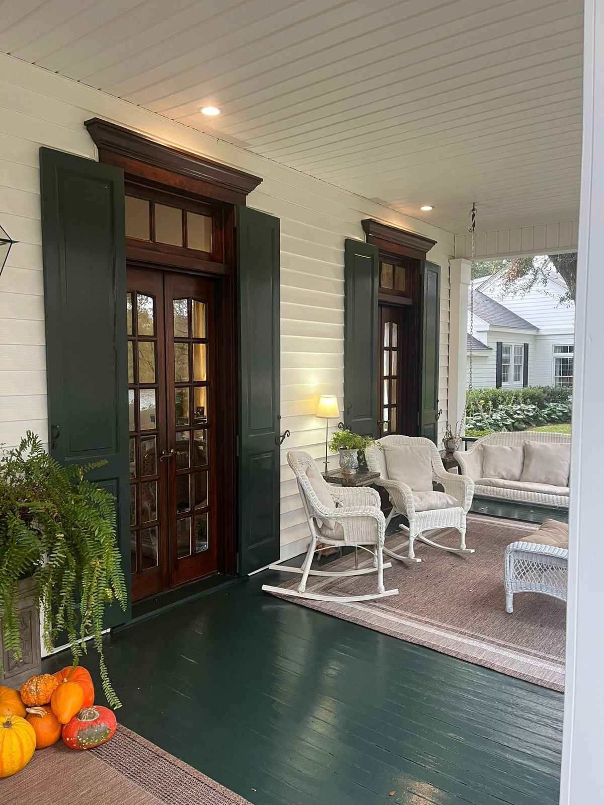 Covered front porch with mahogany French doors and green shutters