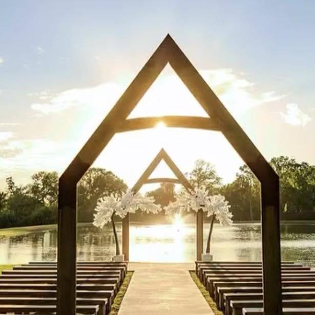A-frame timber ceremony arches by a lake at sunset