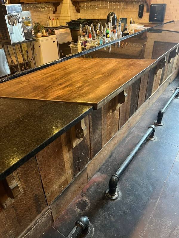 Restaurant bar with reclaimed wood front, wood and granite tops and pipe foot rail
