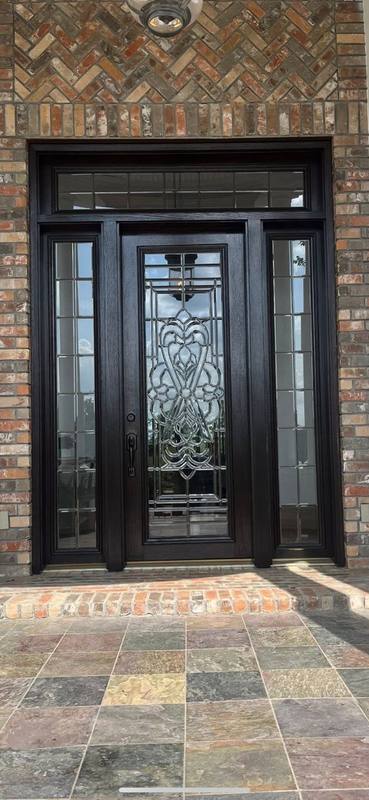 Black entry door with leaded glass, sidelights and transom set in brick